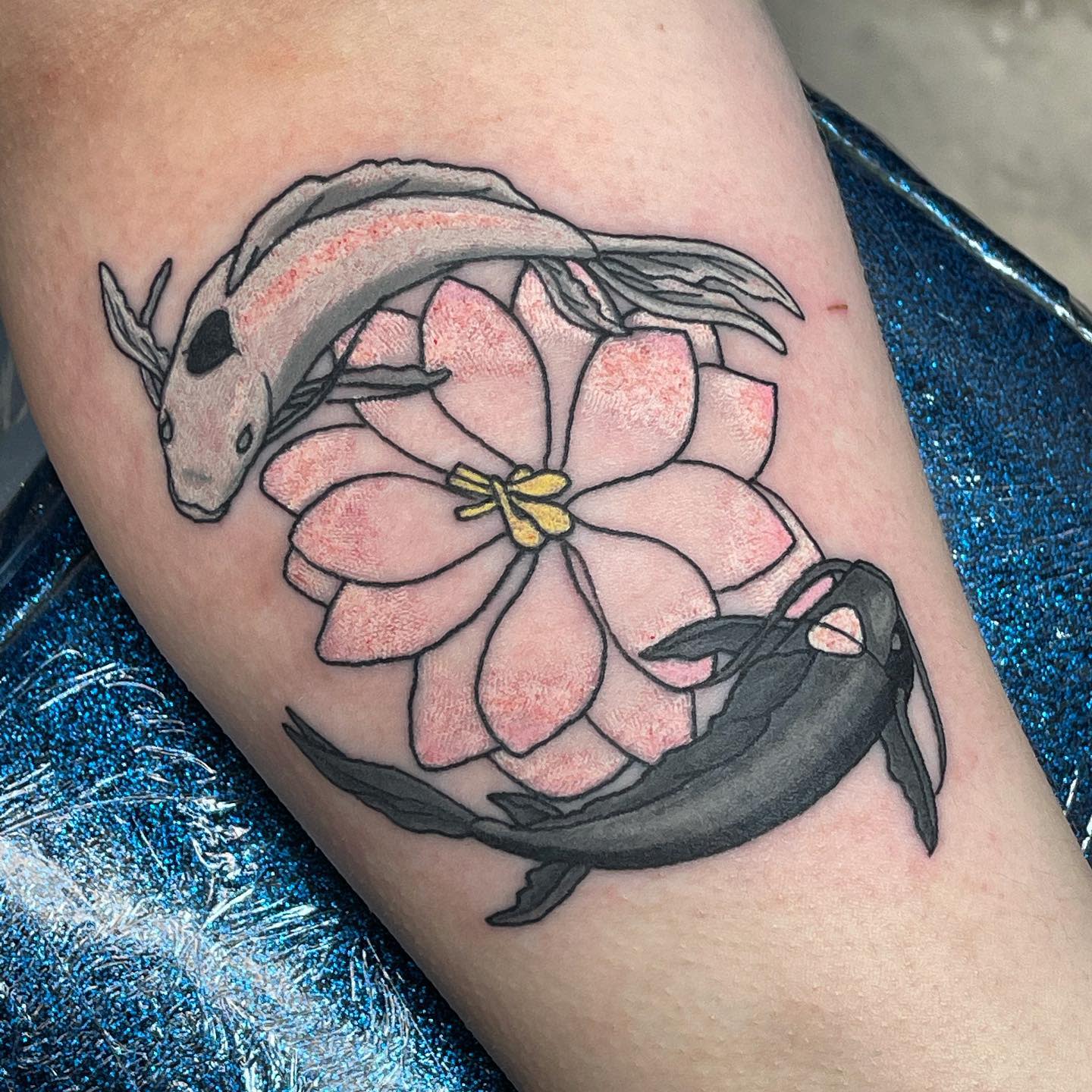 Tattoo of koi fish and pink cherry blossom with yellow center on arm